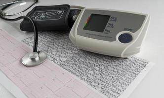 modern elektrisk tonometer och ett stetoskop på ett kardiogramdiagram. hushållets blodtrycksmätare foto