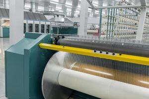 textilgarn på inslagningsmaskinen skruvas fast på det stora skaftet. maskiner och utrustning i en textilfabrik foto
