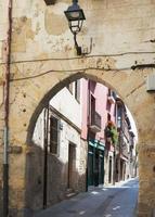 vacker och färgglad gammal gata vid medina de pomar. stenbåge och gatlykta, burgos, merindader, spanien foto