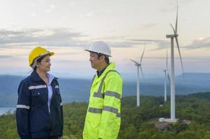 porträtt av människor ingenjör står i ett fält bär en skyddande hjälm på hennes huvud över elektriska turbiner bakgrund. foto