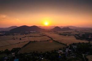 färgglad solnedgång över berg och skördade risfält i jordbruksmark på landsbygden foto