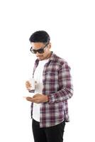 ung hipster man tittar på sin smarta telefon medan textmeddelanden isolerad på vit bakgrund. foto