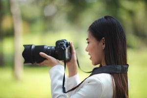 ung asiatisk fotograf kvinna med högteknologisk digitalkamera fotografering foto