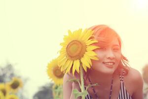vacker sexig kvinna med solros i solrosfält leende mot kameran foto