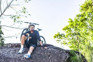 idrottare sitter på berget med cykel foto