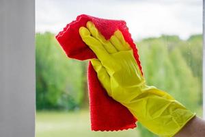 tvätta fönster. kvinna i gula gummihandskar torkar glaset. foto