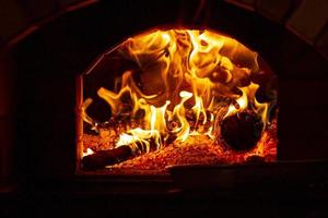 brinnande stock av trä i en öppen spis närbild. foto