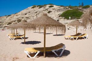 parasoll och solstolar på stranden tidigt på morgonen i väntan på att turisterna ska komma. inga människor, algarve, portugal foto