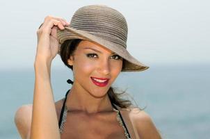 attraktiv kvinna ler med en solhatt på en tropisk strand foto