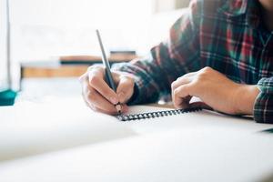 tonårsstudent arbetar med läxor i sitt rum och skriver i en anteckningsbok. foto