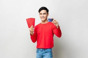leende stilig asiatisk man håller ang pow röda kuvert och kreditkort på studio isolerad ljusgrå bakgrund för kinesiska nyårskoncept foto