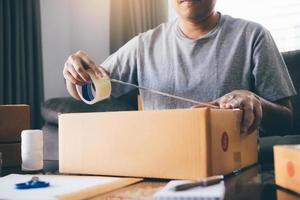 asiatiska entreprenörer tonåringar använder tejpen för att försegla lådan genom att packa produkten för att skicka till kunder. foto