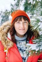 porträtt av en kvinna i en röd varm jacka och hatt i en snöig vinterskog foto