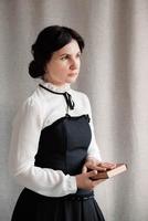 kvinna i vintagestil klädd med en bok i händerna på en bakgrund av linnetyg foto