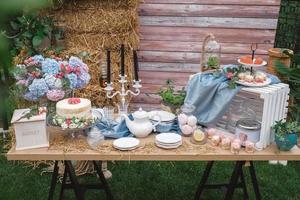 bröllopsgodisbar i rustik stil dekorerad med tallrikar, bestick, glas, ljus och blomsterarrangemang. kopiera, tomt utrymme för text foto