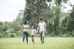 lyckliga föräldrar och deras dotter går i parken, lycklig familj koncept. foto