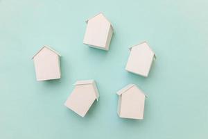 helt enkelt platt låg design med miniatyr vita leksak modell hus isolerade på pastellblå bakgrund. inteckning fastighetsförsäkring drömhem koncept. platt låg ovanifrån kopia utrymme. foto
