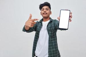 ung indisk collage pojke visar smartphone skärm på vit bakgrund. foto