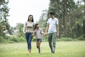 lyckliga föräldrar och deras dotter går i parken, lycklig familj koncept. foto