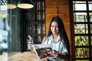 vacker kvinna som läser tidningen i caféet foto