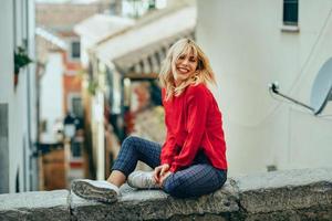 leende blond flicka med röd skjorta njuter av livet utomhus. foto