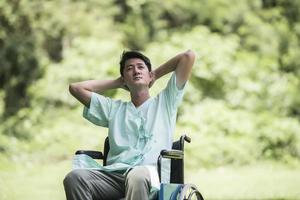 ensam ung handikappad man i rullstol i trädgården foto