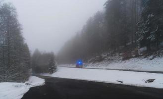 utryckningsbil med ljus på vinterväg i skogen foto