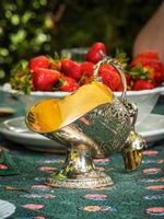 silversockerskål i form av en korg för kol. antika föremål för bordet. eleganta rika rätter för att dekorera en fest. jordgubbar till efterrätt. foto