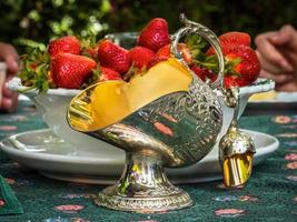 silversockerskål i form av en korg för kol. antika föremål för bordet. eleganta rika rätter för att dekorera en fest. jordgubbar till efterrätt. foto