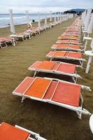 uppradade solstolar på en öde strand en molnig dag. toscana foto