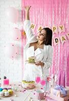 vacker kvinna firar födelsedagsfest som håller en tårta som önskar foto