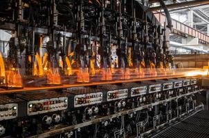 på transportören pastöriseras glasflaskor med eld. fabrik för tillverkning av glasflaskor och drycker foto