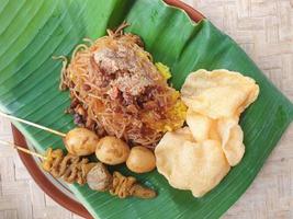 nasi kuning är en traditionell indonesisk rätt som serveras på ett bananblad och tallrik foto