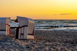 strandstolar står i solnedgången på en strand vid Östersjön med hav foto