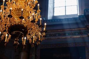 stor bronskrona med elektriska ljus i katedralen kristna kyrkan. dagsljus från fönstret i kyrkan. selektiv fokusering foto