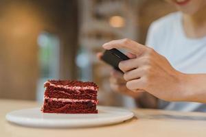 bloggare asiatiska vänliga kvinnor influencer äter tårta på natten café. vacker ung dam glad slappna av roligt med hjälp av teknik mobiltelefon ta ett foto av hennes mat uppladdning i sociala medier på college campus.