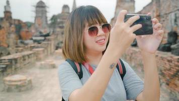 resenär asiatisk kvinna som använder smartphone för att ta en bild medan hon tillbringar semesterresan i ayutthaya, thailand, kvinna njuter av sin resa vid ett fantastiskt landmärke i en traditionell stad. foto
