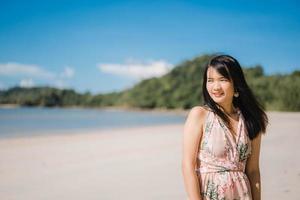 vacker ung asiatisk kvinna koppla av glad promenad på stranden nära havet. livsstil kvinnor reser på stranden koncept. foto