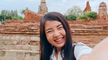 närbild ung asiatisk backpacker bloggare kvinna casual look kamera videosamtal på smartphone dela live online för publiken resa tillsammans på pagoden gamla staden, livsstil turist resor semester koncept. foto