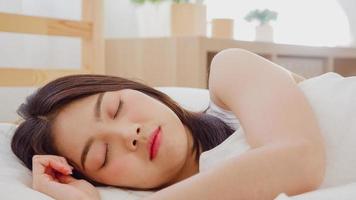 asiatisk kvinna drömmer medan hon sover på sängen i sovrummet, vacker japansk kvinna som använder relaxtid liggande på sängen hemma. livsstil kvinnor använder relaxtid hemma koncept. foto