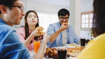 glada unga vänner grupp äta lunch hemma. Asien familjefest äter pizza mat och skrattar njuter av måltid medan du sitter vid matbordet tillsammans hemma. högtid och samvaro. foto