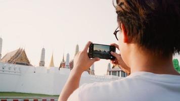 resenär asiatisk man som använder mobiltelefon för att ta en bild medan han tillbringar semesterresan i bangkok, thailand, manlig njut av resan vid ett fantastiskt landmärke i solnedgången. livsstil män reser i staden koncept. foto