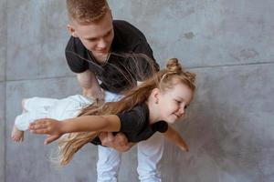 kaukasiska syskon - tonåring pojke bror och lilla flicka syster som leker i flygplan i modern loft interiör på grå cement bakgrund foto