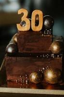 födelsedagchokladkaka med ett nummer trettio. dekorerad med gyllene chokladbollar. Grattis på födelsedagen foto