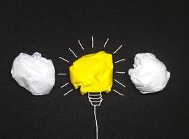 kreativ idébakgrund, glödlampa gjord av en gul pappersboll foto