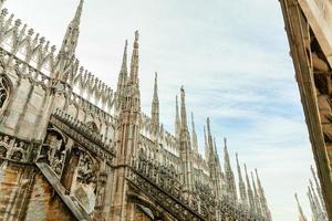 taket på katedralen i milano duomo di milano med gotiska spiror och statyer i vit marmor. topp turistattraktion på piazza i Milano, Lombardiet, Italien. vidvinkelvy av gammal gotisk arkitektur och konst. foto