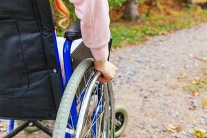 hand handikapp kvinna i rullstol hjul på väg i sjukhus park väntar på patienttjänster. oigenkännlig förlamad tjej i invalid stol för funktionshindrade utomhus. rehabiliteringskoncept. foto