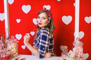 vacker ung kvinna i pin-up stil på rött med vita hjärtan bakgrund foto