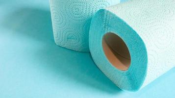 blå rulle av modernt toalettpapper på en blå bakgrund. en pappersprodukt på en kartonghylsa, använd för sanitära ändamål av cellulosa med utskärningar för enkel rivning. präglad ritning. kopieringsutrymme. foto