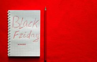 svart fredag rea text skriven på ett anteckningsblock med en röd penna på en röd bakgrund. bakgrund, semester koncept. svart fredag - internationell dag för shopping, kampanjer, rabatter, reor. foto